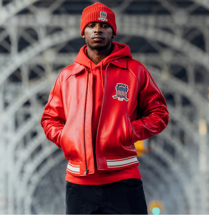 Person wearing a red jacket and beanie standing in front of a bridge